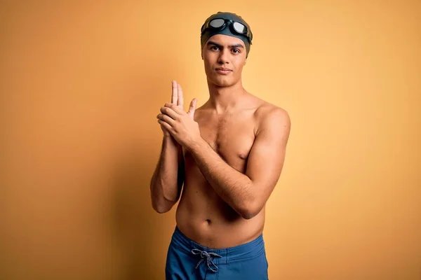 年轻英俊的男子赤身裸体 身穿泳衣 头戴一顶淡黄的泳帽 手拿着象征性的枪 玩着猎枪 满脸怒容 — 图库照片
