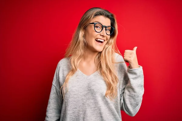 Jovem Mulher Loira Bonita Vestindo Suéter Óculos Sobre Fundo Vermelho — Fotografia de Stock