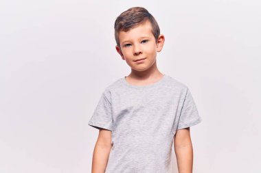 Yüzünde ciddi bir ifade olan sıradan kıyafetler giyen sevimli sarışın çocuk. Basit ve doğal bir şekilde kameraya bakıyorsun.. 