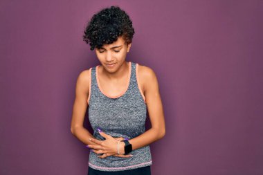 Genç ve güzel Afro-Amerikan Afro-Amerikan spor kadın spor giyiniyor. Spor kıyafetlerini midesi üstünde giyiyor. Çünkü hazımsızlık, acı verici hastalıklar kendini iyi hissetmiyor. Ache kavramı.
