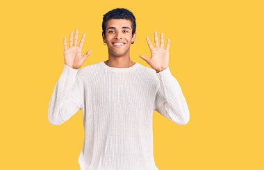 Genç Afrikalı Amerikalı günlük kıyafetler giymiş on numarayı gösterip işaret ederken kendinden emin ve mutlu gülümsüyor.. 