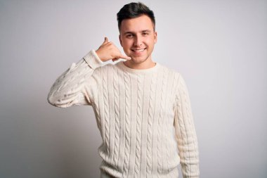 Beyaz izole edilmiş arka planda sıradan bir süveter giyen beyaz, yakışıklı beyaz bir adam telefonla el ve parmaklarıyla telefonla konuşuyor gibi gülümsüyor. İletişim kavramları.