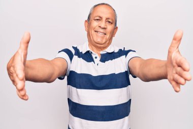 Gri saçlı, sıradan çizgili polo giyen son sınıf öğrencisi kucaklaşmak için kollarını açmış kameraya bakıyor. Mutluluğu kucaklayan neşeli bir ifade.. 