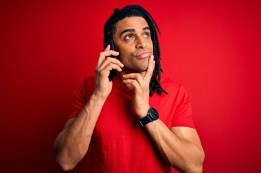 Afrika kökenli Afro Amerikalı genç bir adam. Rastalı bir şekilde konuşuyor. Akıllı telefondan konuşuyor.