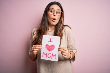 Elinde aşk dolu bir kağıt tutan genç bir kadın. Anneler gününü kutlayan bir mesaj. Şaşırmış bir yüzle korkmuş ve korku ifadesinden heyecanlanmış bir şekilde.