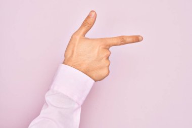İzole edilmiş pembe arka plan üzerinde parmaklarını gösteren beyaz bir gencin eli işaret parmağıyla kenarı işaret ediyor ve bir seçim yapıyor.