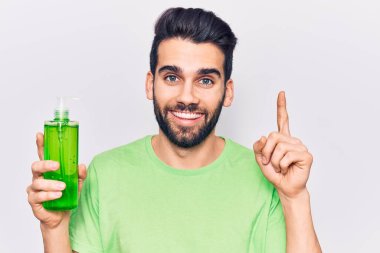 Sakallı, aloe vera kremi sürmüş genç yakışıklı bir adam bir fikir ya da soruyla gülümsüyor ve mutlu bir yüzle işaret ediyor. 