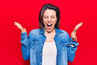 Gündelik giysiler giyen genç, çılgın ve çılgın başarıyı kutlayan kollarını kaldırmış, gözlerini kapatmış heyecanlı çığlıklar atan bir kadın. Kazanan konsept 