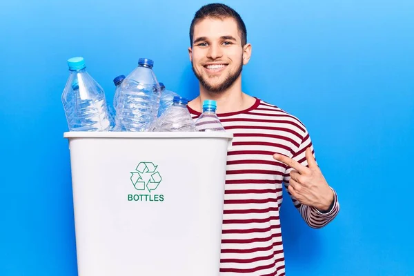 若いですハンサムな男リサイクルプラスチックボトル笑顔幸せなポインティングとともに手と指 — ストック写真