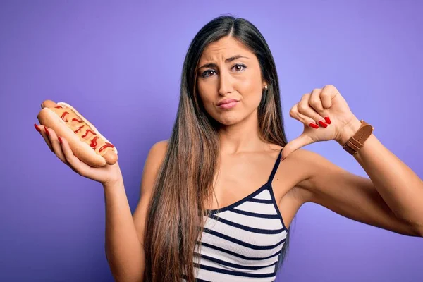 Jovem Comendo Cachorro Quente Com Ketchup Mostarda Sobre Fundo Roxo — Fotografia de Stock