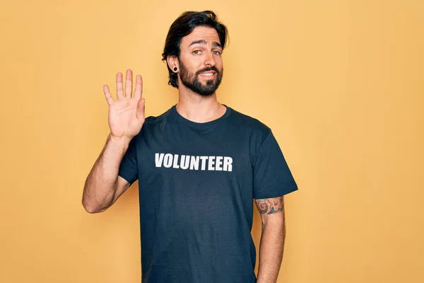 若いハンサムなパニックボランティア男性ボランティアTシャツを社会的ケアとして身に着けているこんにちは幸せと笑顔 優しい歓迎のジェスチャー — ストック写真