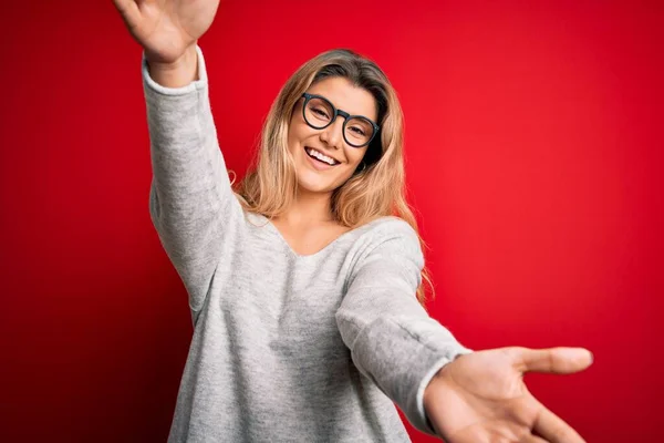 Jovem Mulher Loira Bonita Vestindo Suéter Óculos Sobre Fundo Vermelho — Fotografia de Stock