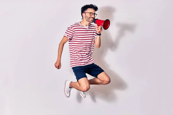 Young Handsome Hispanic Man Wearing Glasses Screaming Using Megaphone Jumping — Stock Photo, Image