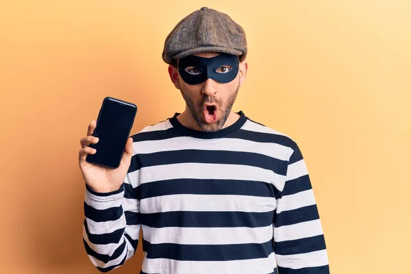 Νέος Όμορφος Φαλακρός Άνδρας Φορώντας Μάσκα Διαρρήκτη Κρατώντας Smartphone Φοβισμένος — Φωτογραφία Αρχείου