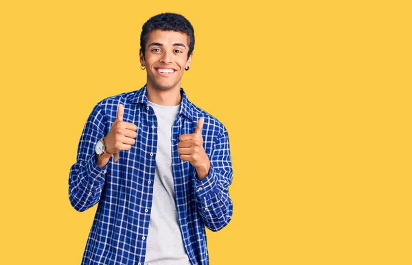 カジュアルな服を着ている若いアフリカ系アメリカ人の男性は 手で積極的なジェスチャーを行い 親指を笑顔と幸せ 陽気な表情と勝者のジェスチャー — ストック写真