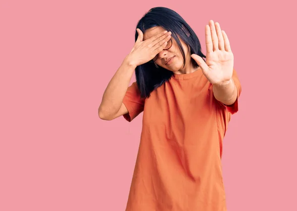 Young beautiful latin woman wearing casual clothes covering eyes with hands and doing stop gesture with sad and fear expression. embarrassed and negative concept.