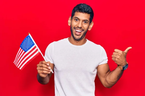 Joven Latino Sosteniendo Bandera Estados Unidos Apuntando Con Pulgar Hacia —  Fotos de Stock