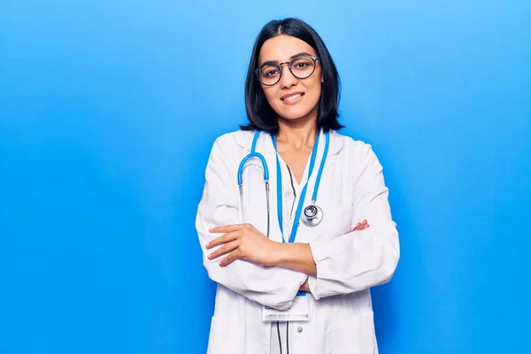 Young beautiful latin woman wearing doctor stethoscope and id card happy face smiling with crossed arms looking at the camera. positive person.