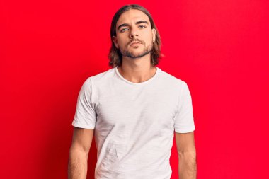 Gündelik kıyafetler giyen genç yakışıklı adam yüzünde ciddi bir ifadeyle rahatlamış. Basit ve doğal bir şekilde kameraya bakıyorsun.. 