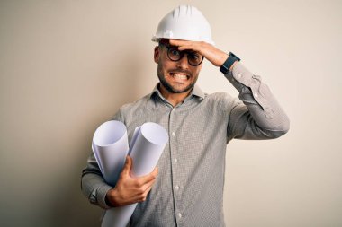 Müteahhit miğferi takan genç bir mimar, proje kâğıt planını izole edilmiş arka planda tutarken el ele, utanç ve şaşkınlık dolu yüzlerle, sinirli ve hayal kırıklığına uğramış bir şekilde vurguladı. Hata için korku ve üzüntü.