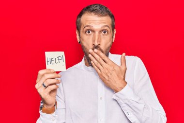 Elinde genç yakışıklı bir adam var. Ağzını eliyle kapatıyor. Şok geçiriyor ve hata yapmaktan korkuyor. şaşırmış ifade 