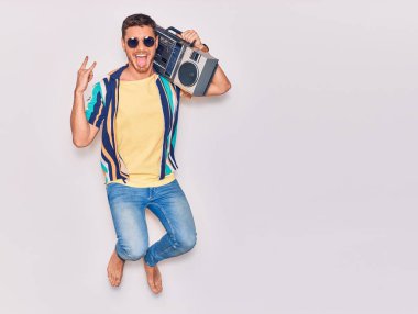 Ağzı ve ağzı açık güneş gözlüğü takan yakışıklı bir İspanyol. Müzik kutusunu tutarak şarkı söyleyerek soyutlanmış beyaz arka planda zıplayarak