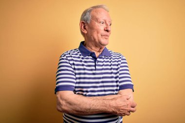 Gri saçlı, donanma çizgili tişört giyen, sarı arka planda dikilmiş gülümseyen ve başka yöne bakan son sınıf öğrencisi..