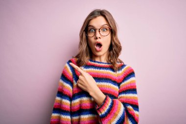 Genç, sarışın, gözlüklü ve pembe izole edilmiş arka planda sıradan bir süveter giyen güzel bir kız..
