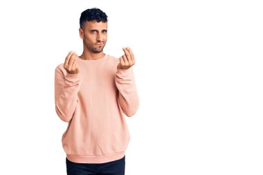 Gündelik kıyafetler giyen genç İspanyol adam elleriyle para hareketi yapıyor, maaş istiyor, milyonerlik işi yapıyor. 