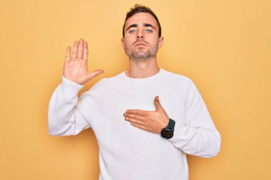 Mavi gözlü genç adam sarı arka planda dikilmiş el pençe divan duran sadakat yemini ediyor.