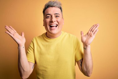 Sarı arka plan üzerine sarı tişört giyen genç ve modern bir adam çılgın ve başarıyı kollarını kaldırıp heyecanla haykırarak kutluyor. Kazanan konsept