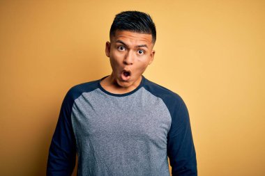 Sarı arka planda dikilen sıradan tişörtlü genç, yakışıklı Latin adam korku ve heyecan dolu bir yüz ifadesiyle dehşete düşmüş ve şok olmuştu..