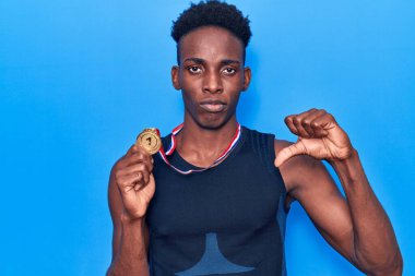 Afro-Amerikalı genç adam spor giysisi takıyor kızgın suratlı, negatif işaretli baş parmakları aşağıda, reddedilme konsepti. 