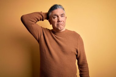 Orta yaşlı, yakışıklı, gri saçlı, sarı arka planda rahat süveter giyen ve soru sormayı seven bir adam. Şüpheyle kararsız, kafa kafaya düşünerek. Düşünceli kavram.