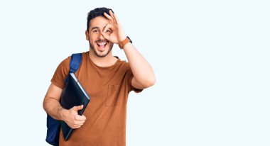 Sırt çantasında öğrenci çantası taşıyan genç İspanyol adam gülümsüyor. Mutluluktan gülümsüyor. 