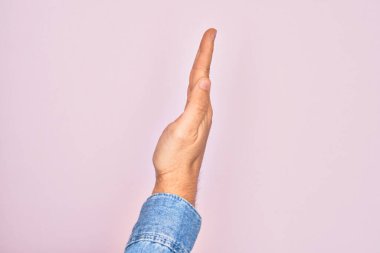 Kafkasyalı bir gencin elleri pembe arka planda parmaklarını gösteriyor. Uzanmış el hareketlerini gösteriyor.