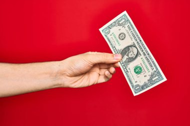 Güzel bir el, bir dolarlık banknotu izole edilmiş kırmızı arka planda tutuyor.