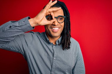 Rastgele gömlek ve gözlük takmış, el hareketleriyle gülümseyen, mutlu yüzüyle parmaklarının arasından bakan yakışıklı Afro-Amerikalı genç adam..