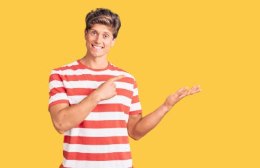 Gündelik kıyafetler giyen genç yakışıklı adam kameraya hayret ediyor ve gülümsüyor.. 