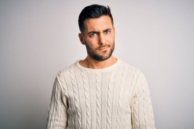 İzole edilmiş beyaz arka plan üzerinde duran sıradan bir süveter giyen genç yakışıklı şüpheli ve gergin, sorun yüzünden üzgün. Negatif kişi.