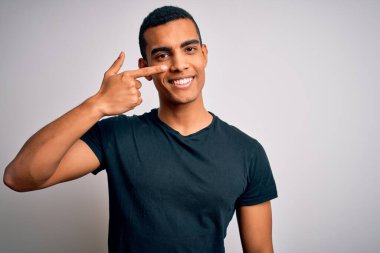 Beyaz arka planda duran, elleri ve burunları işaret eden, neşeli gülümseyen gündelik tişörtler giyen Afro-Amerikan genç adam. Güzellik konsepti