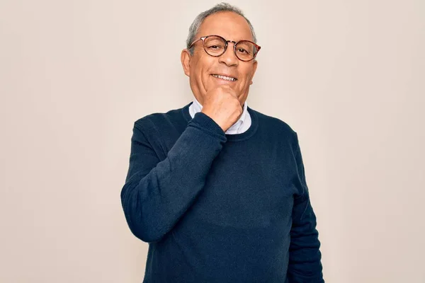 Senior handsome grey-haired man wearing sweater and glasses over isolated white background looking confident at the camera with smile with crossed arms and hand raised on chin. Thinking positive.