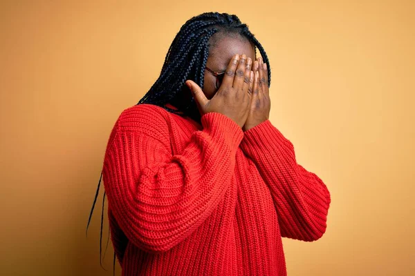 泣きながら手で顔を覆う悲しい表情で黄色の背景にカジュアルなセーターを身に着けている編組とアフリカ系アメリカ人プラスサイズの女性 うつ病の概念 — ストック写真
