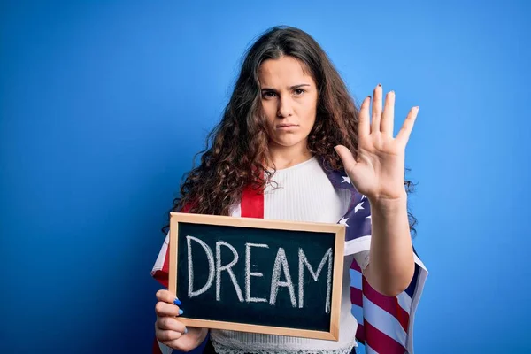 美丽的爱国妇女 身穿美国国旗 拿着写着梦想信息的黑板 张开双臂 严肃而自信地做着停止手势 做着防御手势 — 图库照片