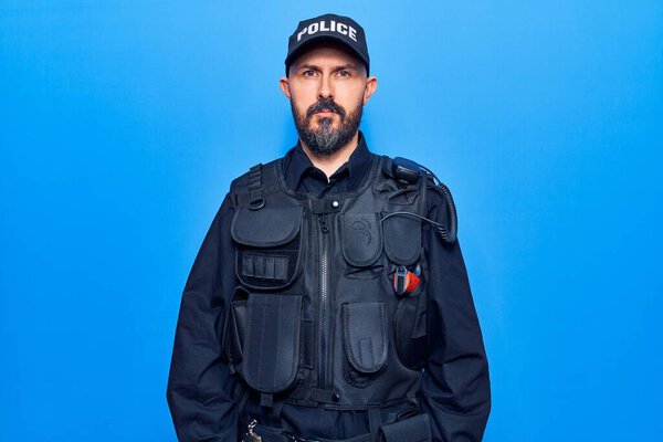 Young handsome man wearing police uniform with serious expression on face. simple and natural looking at the camera. 