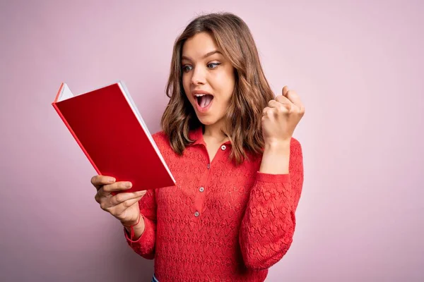 Joven Estudiante Rubia Leyendo Libro Sobre Fondo Rosa Aislado Gritando — Foto de Stock