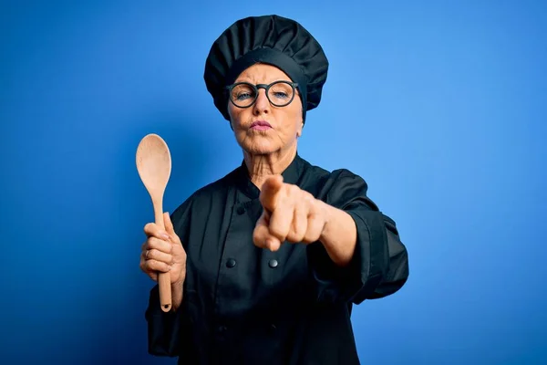 高级漂亮的白发女厨师身穿炊事服 头戴木勺帽 手指指向相机和你 正面积极自信的手势 — 图库照片