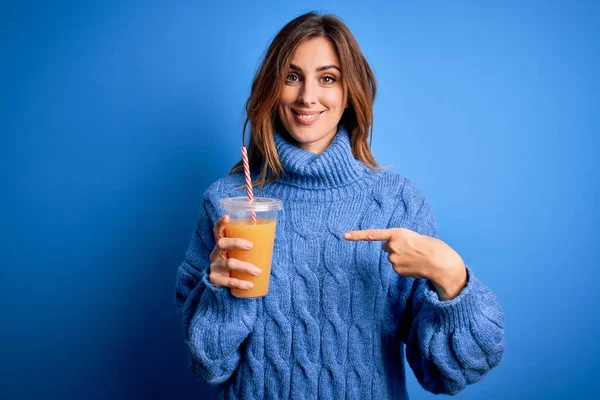 Junge Schöne Brünette Frau Trinkt Gesunden Orangensaft Über Blauem Hintergrund — Stockfoto