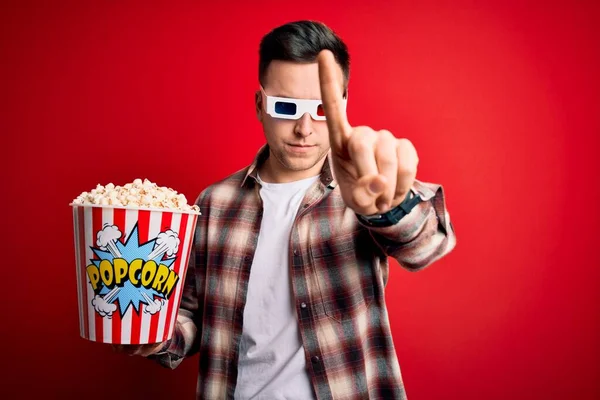 年轻英俊的高加索男子戴着3D电影眼镜 带着愤怒的表情 带着手指尖尖吃爆米花 毫无表情 — 图库照片