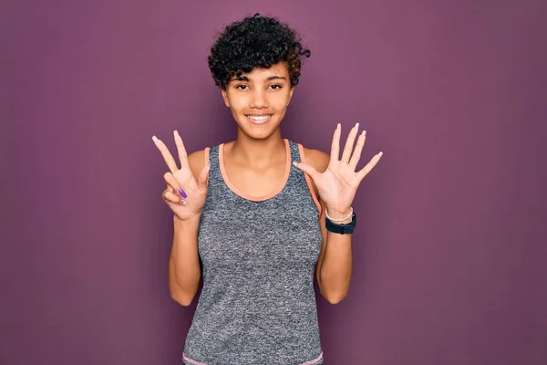 若い美しいアフリカ系アメリカ人のアフロスポーツ女性は自信と幸せ笑顔ながらスポーツウェアを着て指数8で見上げと指摘を行う — ストック写真
